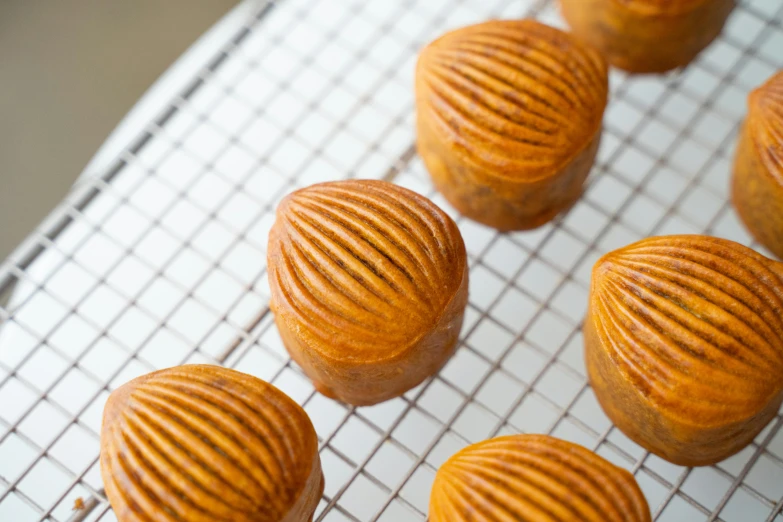 a bunch of cookies sitting on top of a cooling rack, hurufiyya, with a bundt bundt pan face, close up iwakura lain, hand carved brown resin, thumbnail