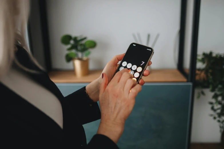 a close up of a person holding a cell phone, trending on pexels, tactile buttons and lights, corporate phone app icon, at home, lightly dressed