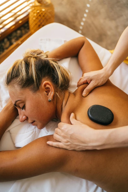 a woman getting a hot stone massage, by Niko Henrichon, unsplash, square, brazilian, blond, lush surroundings
