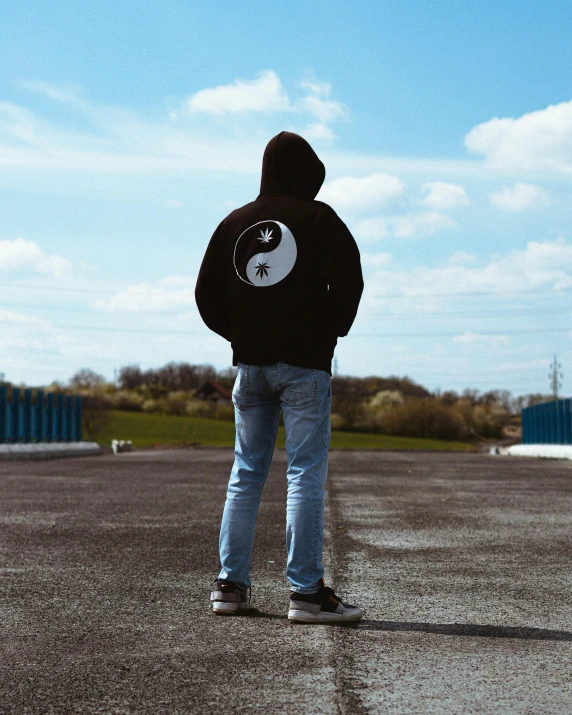 a man in a black hoodie looks off into the distance