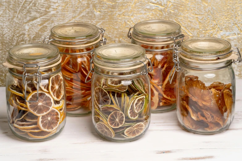 a group of jars sitting on top of a wooden table, orange slices, hair loopies, full product shot, dried flower