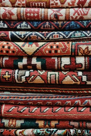 a pile of colorful rugs stacked on top of each other, by Jessie Algie, trending on unsplash, tribal red atmosphere, intricate parts, inspect in inventory image, cinematic still