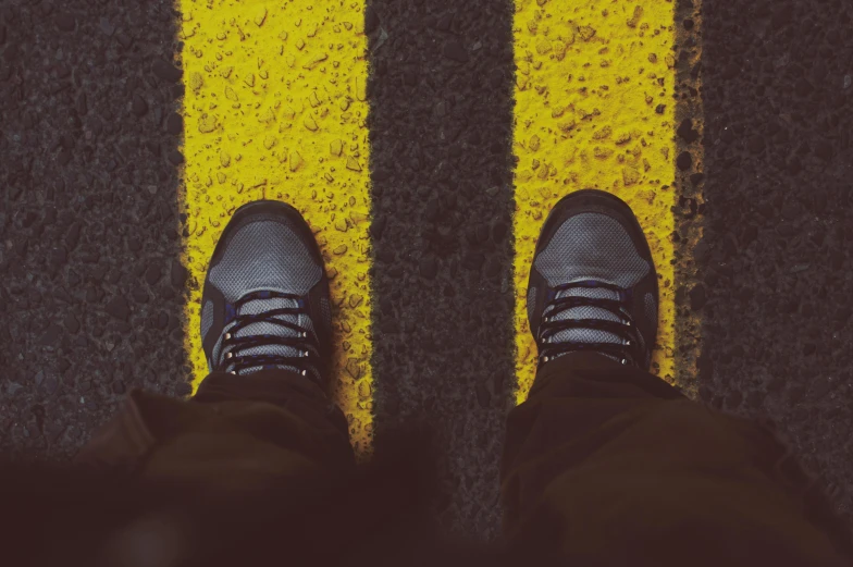 a person standing in the middle of a yellow line, trending on pexels, black shoes, yellow and charcoal leather, grungy, childish