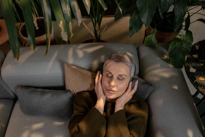 a woman laying on a couch talking on a cell phone, inspired by Elsa Bleda, trending on pexels, headphones on head, woman made of plants, old woman, bang olufsen