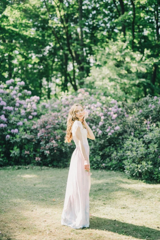 a woman in a white dress standing in a field, inspired by Oleg Oprisco, unsplash, romanticism, lilac, 15081959 21121991 01012000 4k, medium format. soft light, standing in a botanical garden