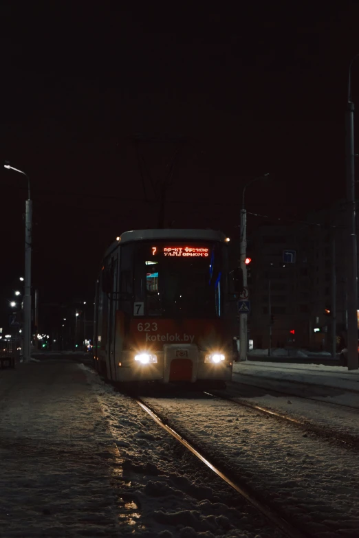 a city bus is driving down the street at night