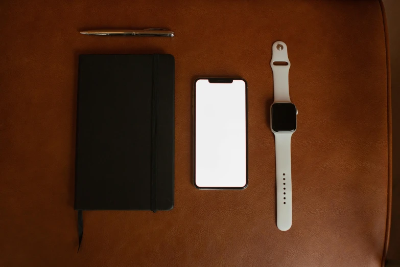 a cell phone sitting on top of a table next to a notebook, a still life, by Andrei Kolkoutine, minimalism, iphone 1 3 pro max, square, overview, white soft leather model