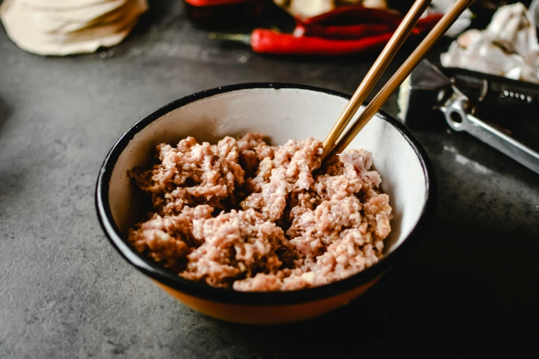 a bowl of food with chopsticks in it, a portrait, ground meat, covered in pink flesh, mortar and pestle, up close image