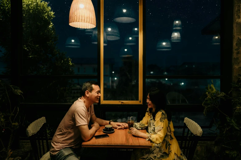 a man and a woman sitting at a table, by Lee Loughridge, pexels contest winner, predawn, hoang lap, slight overcast, cafe lighting