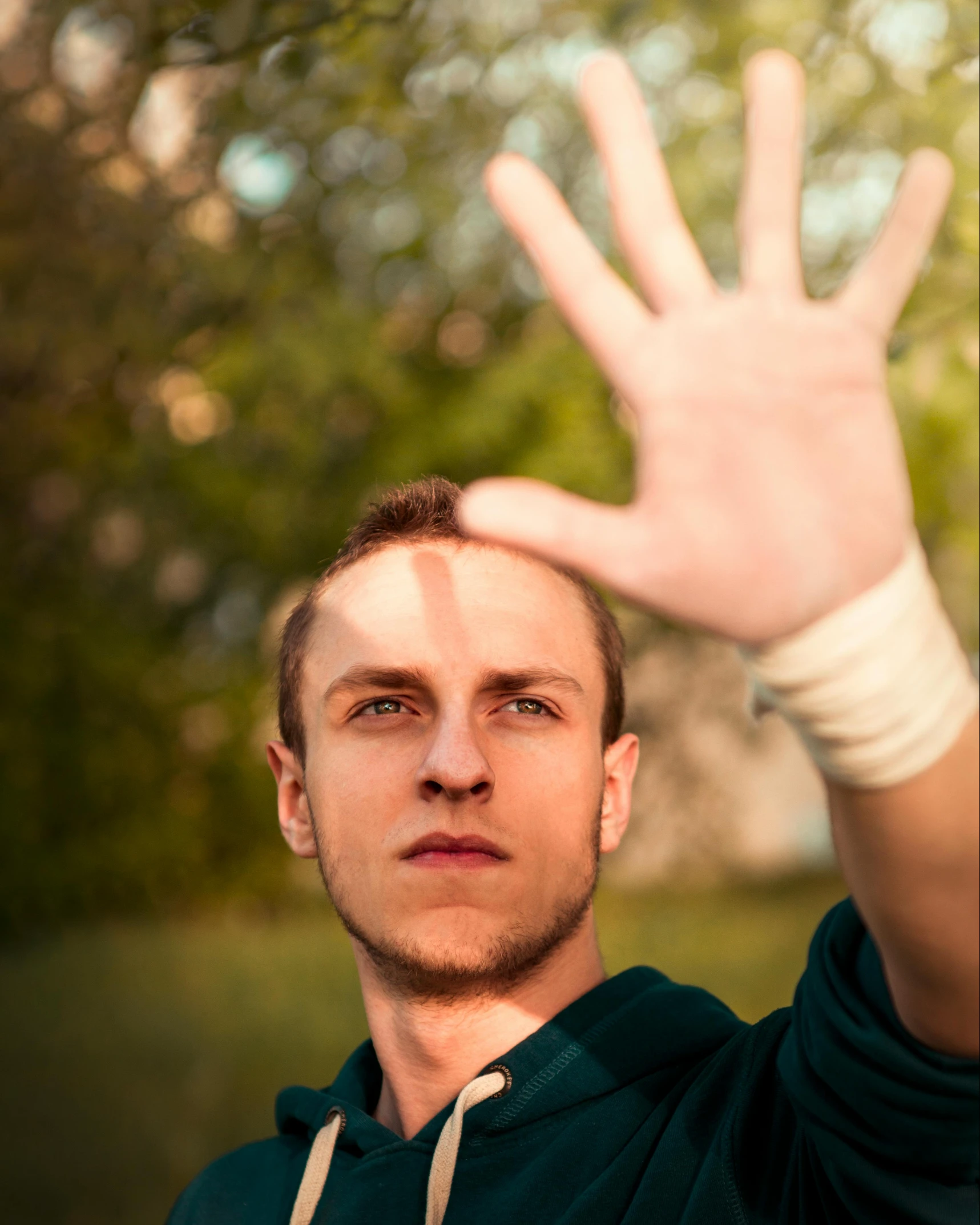 a young man in green holds up his hand and poses