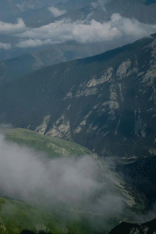 a horse stands on a green hill, surrounded by clouds