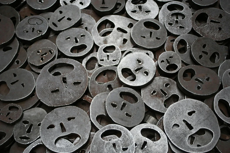 a pile of metal keys sitting on top of a table, mingei, well drawn faces, round shapes, scarred face, smiling mask