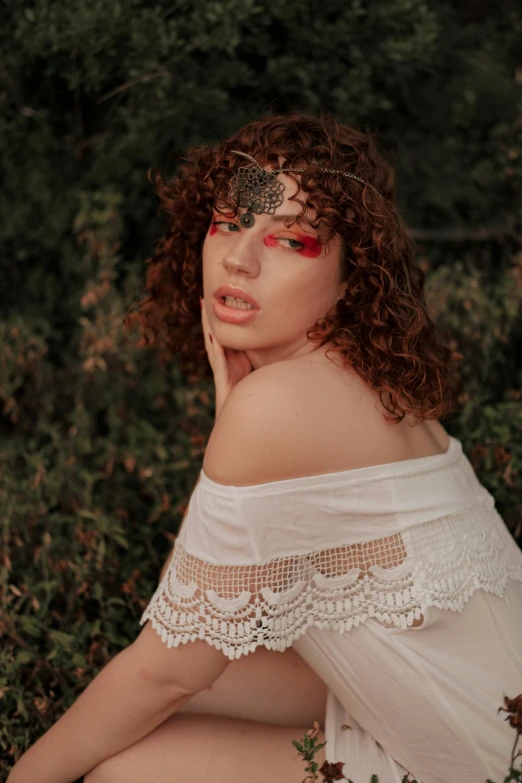 a woman sitting on top of a lush green field, an album cover, inspired by Elsa Bleda, trending on pexels, renaissance, red curly hair, white facepaint, close up portrait photo, white lace clothing