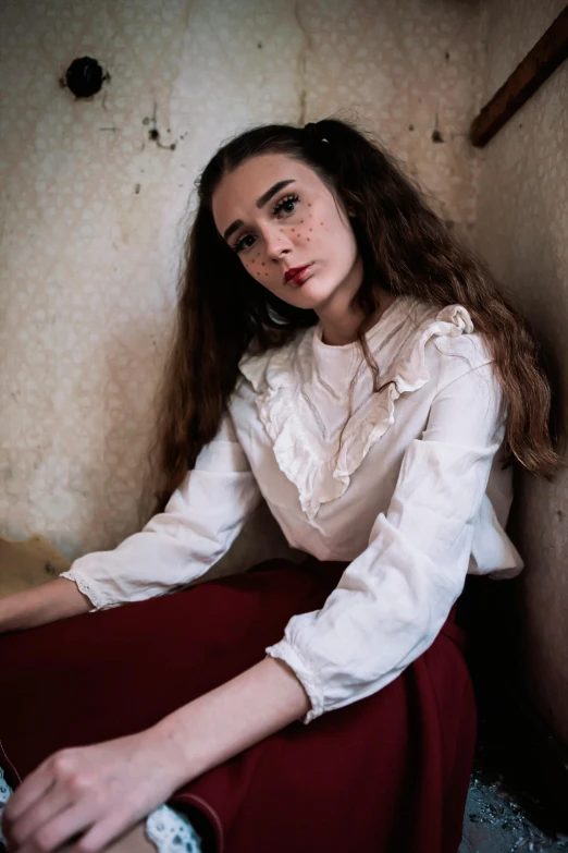 a woman sitting on the floor in a room, an album cover, inspired by Elsa Bleda, pexels contest winner, renaissance, dressed in a frilly ((ragged)), white wrinkled shirt, teenager, wearing victorian rags