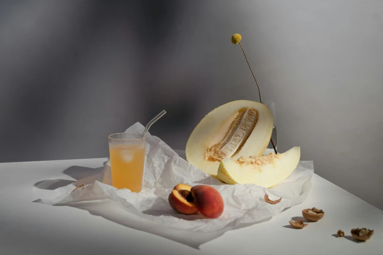 a piece of melon sitting on top of a table next to a glass of juice, a still life, inspired by Jacopo Bellini, unsplash, photorealism, on grey background, with a straw, melanchonic soft light, various posed