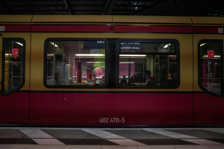 a red and yellow train sitting inside of a train station, unsplash, hyperrealism, magenta, people at work, berlin, 2000s photo