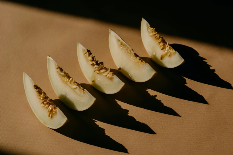 a group of slices of melon sitting on top of a table, inspired by Kay Sage, trending on pexels, shadow play, back - lit, long claws, apple