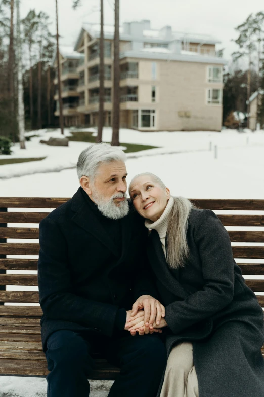 an old couple sits together on a park bench