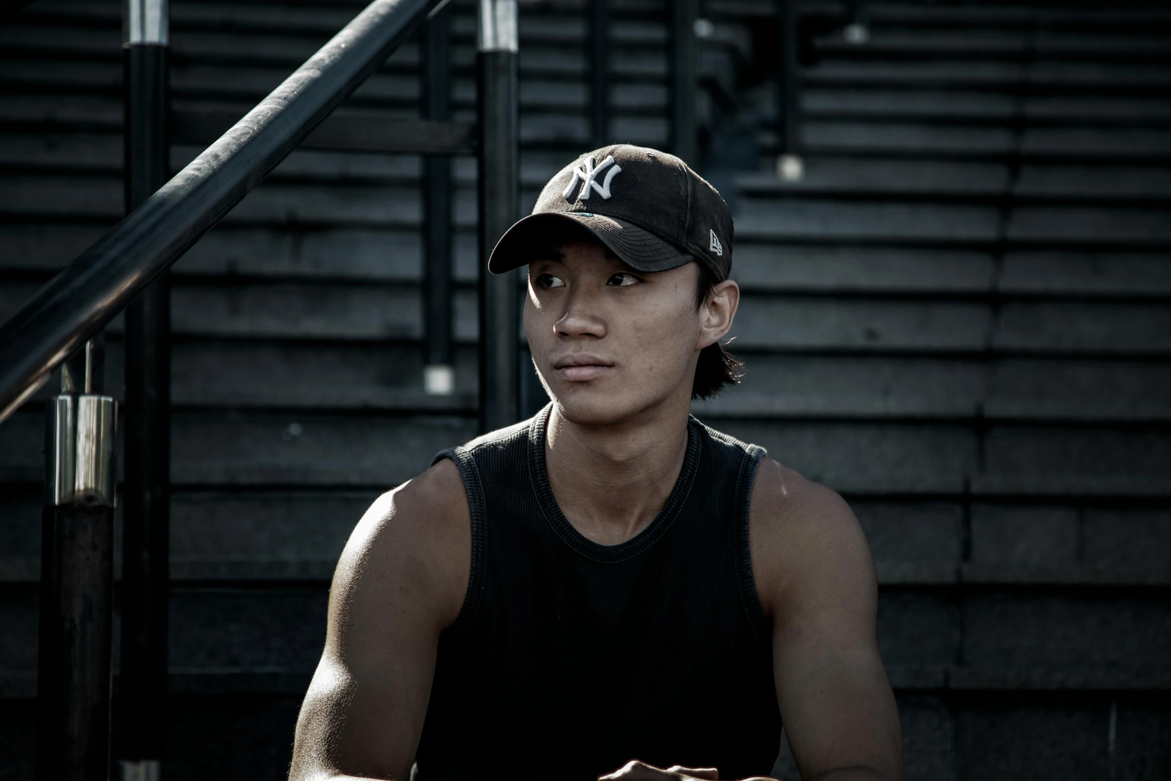 a person wearing a baseball cap sits on some steps