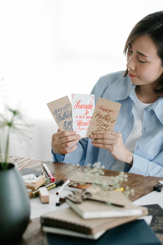 a woman sitting at a table reading a book, private press, greeting card, estrange calligraphy, crafts and more, joy ang