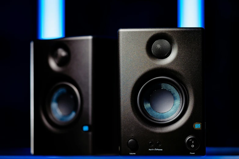 a pair of speakers sitting on top of a table, symmetric azure eyes, in front of a computer, studio lit, blue steel