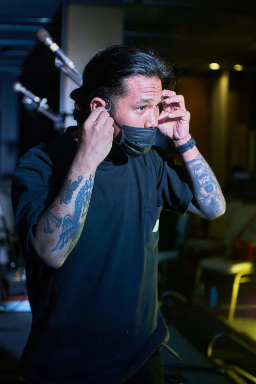 a man with tattoos talking on a cell phone, wearing a mask, hideki anno, wearing black headphones, slide show