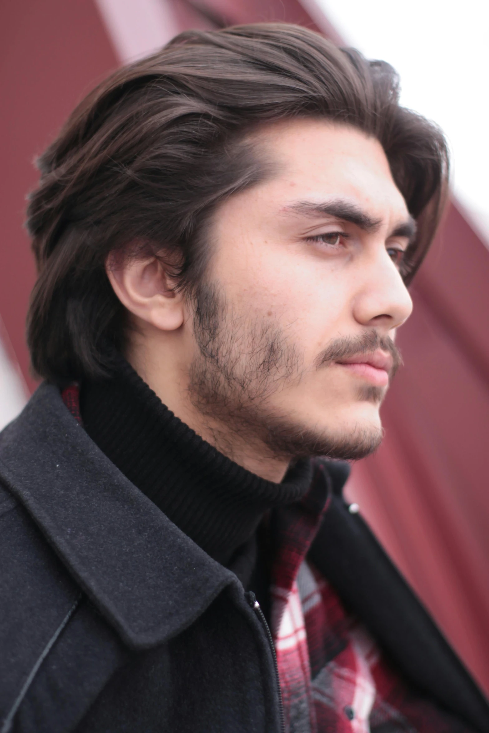 a man looking away while standing in front of a wall