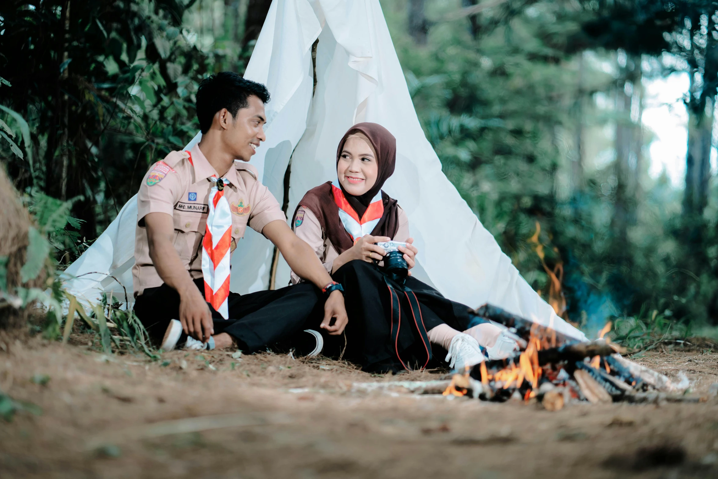 a man and a woman sitting next to a campfire, a picture, by Basuki Abdullah, pexels contest winner, hurufiyya, handsome girl, scout boy, thumbnail, roleplay