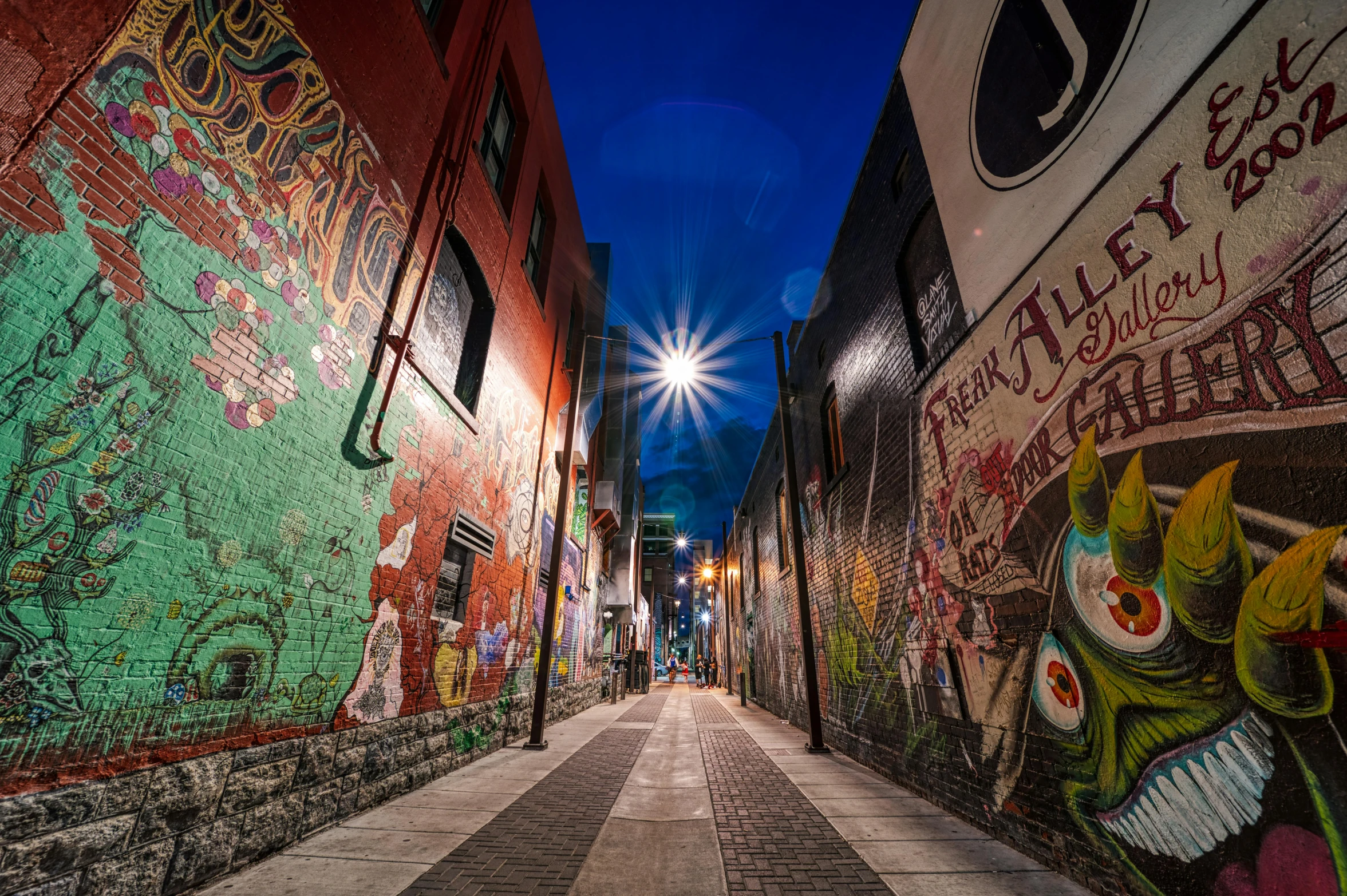 a street filled with lots of graffiti next to a tall building, pexels contest winner, in an alley at night back lit, indigenous art, anfree wallin, we go