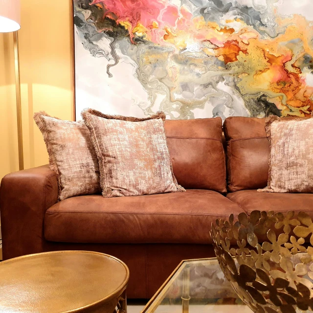 a living room filled with furniture and a large painting, inspired by david rubín, trending on pixabay, leather sofa, brown and pink color scheme, accented in bright metallic gold, close up details