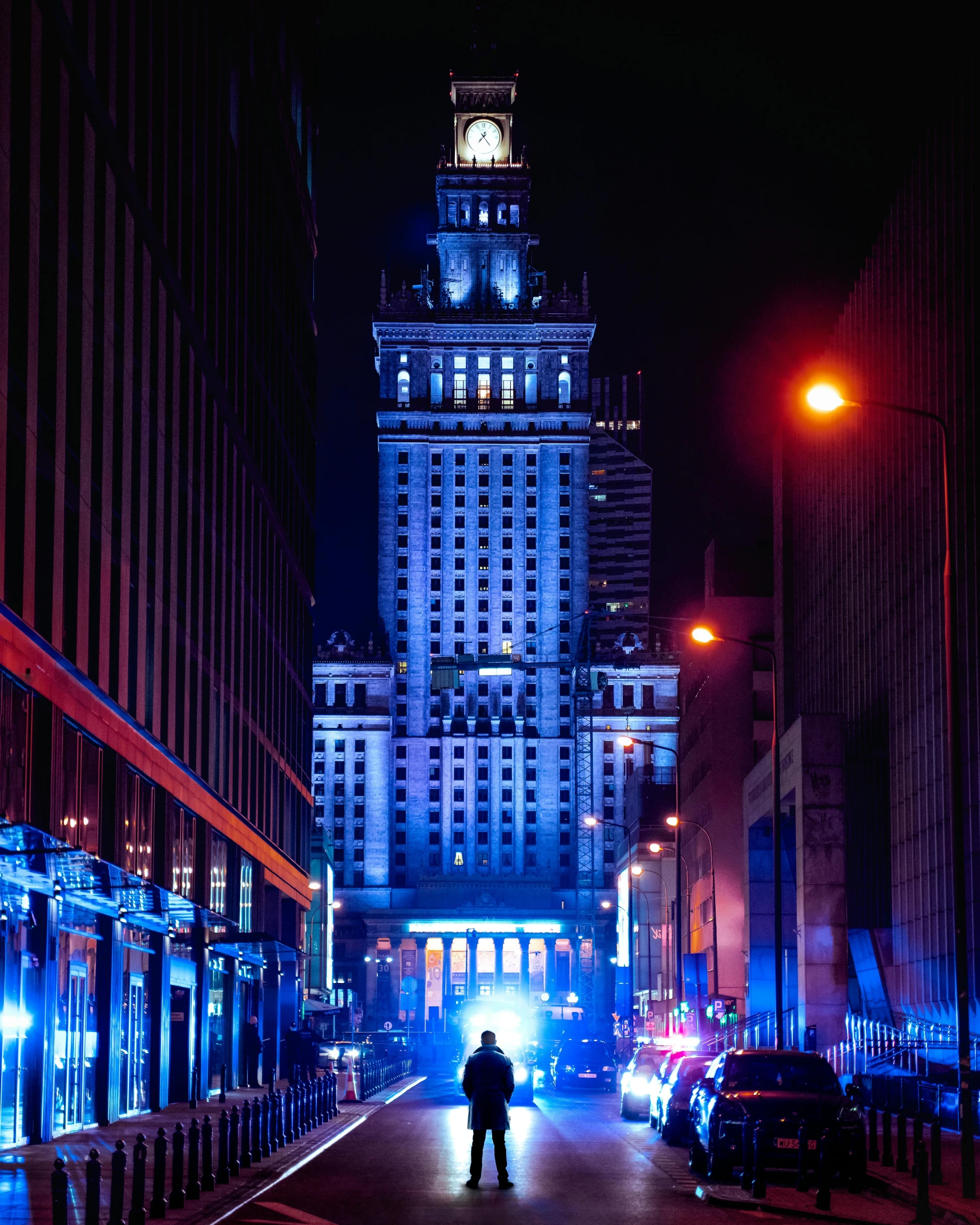 man standing on a street at night in a city