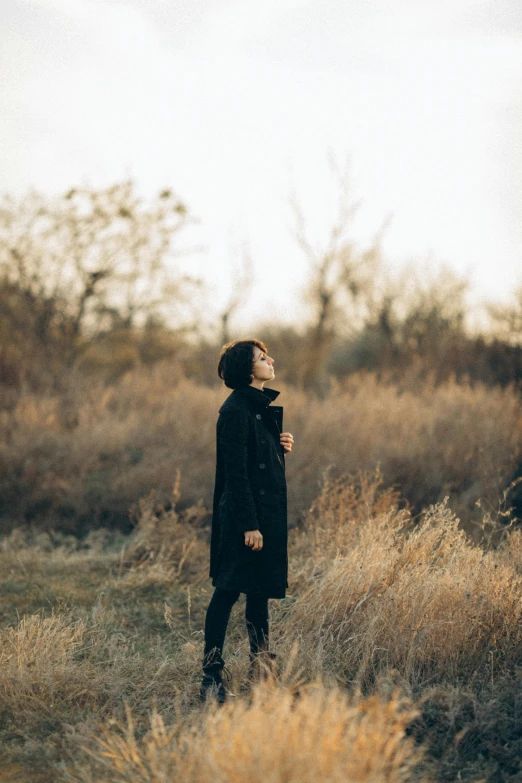 a person standing in the grass wearing a jacket