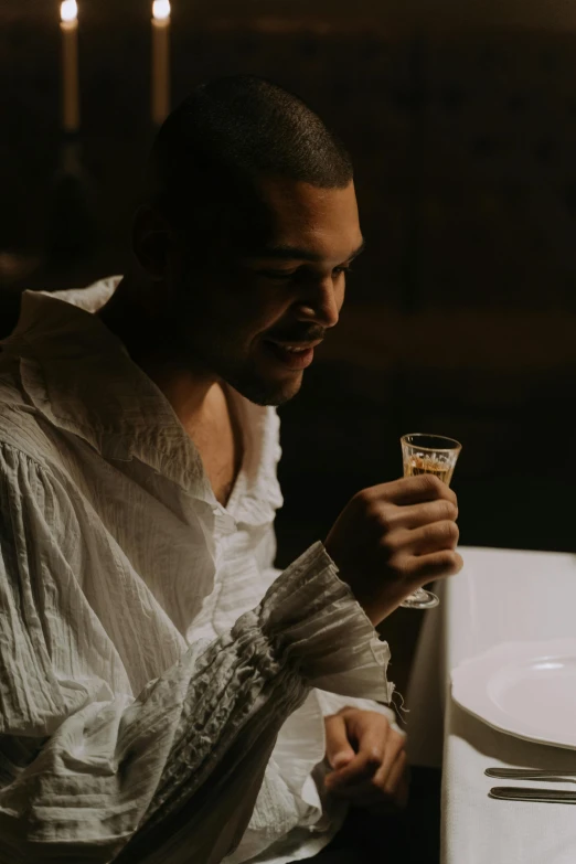 a man holding a glass on top of a table