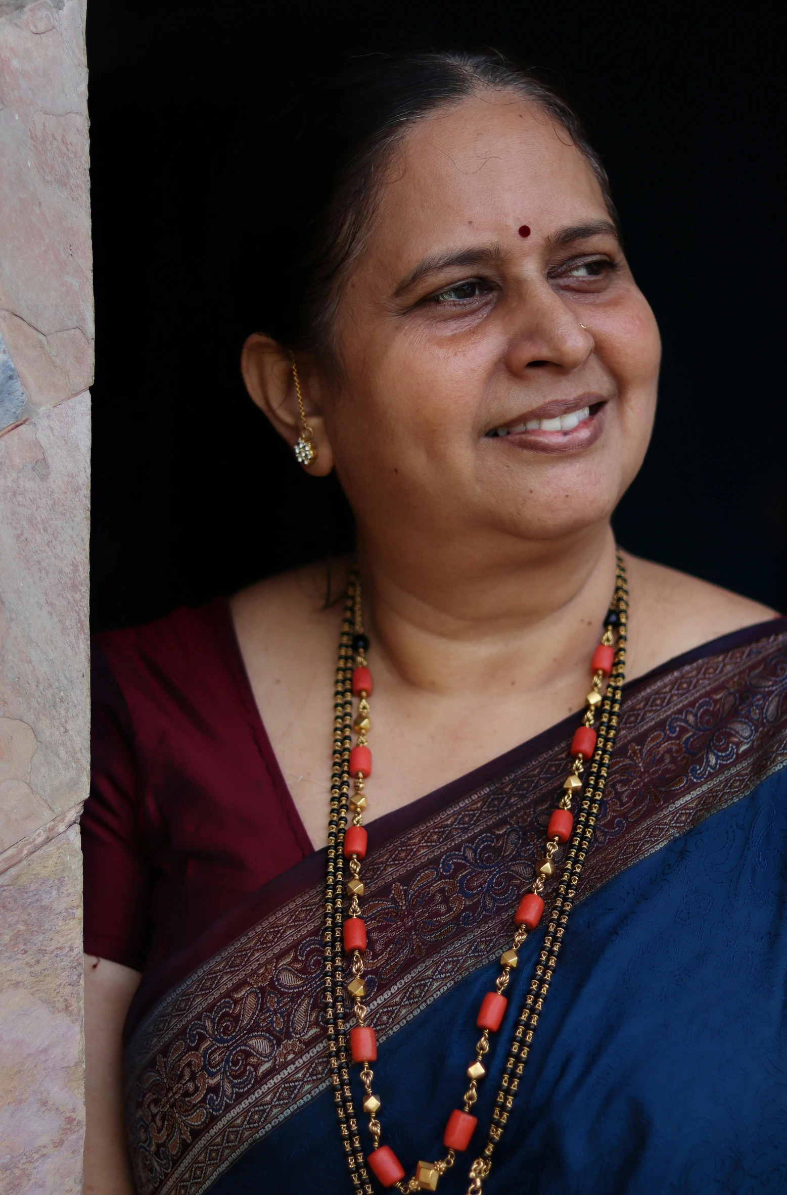 a woman in a sari looking out of a window, while smiling for a photograph, profile image, wearing jewellery, taken in the late 2010s