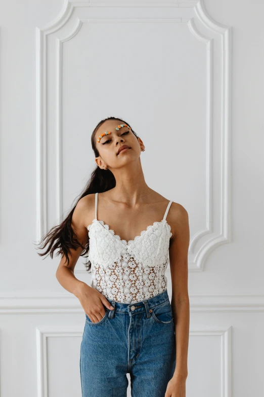 a woman standing in front of a white wall, by Robbie Trevino, trending on pexels, renaissance, dressed in a lacy, vanessa morgan, wearing a camisole, modeling shoot