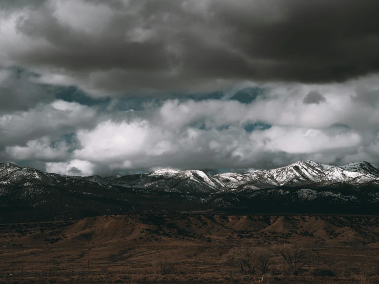 a few snow capped mountains under clouds on a cloudy day