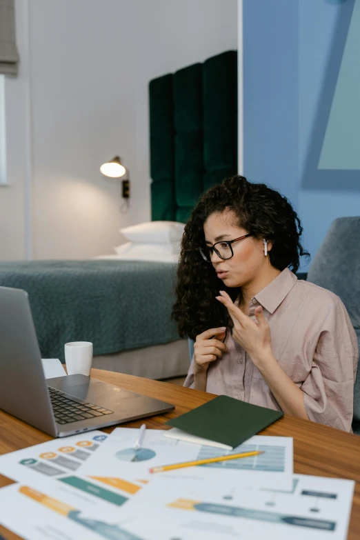 a woman sitting at a desk in front of a laptop, trending on pexels, looking confused, sitting on a bed, with pointing finger, - 9