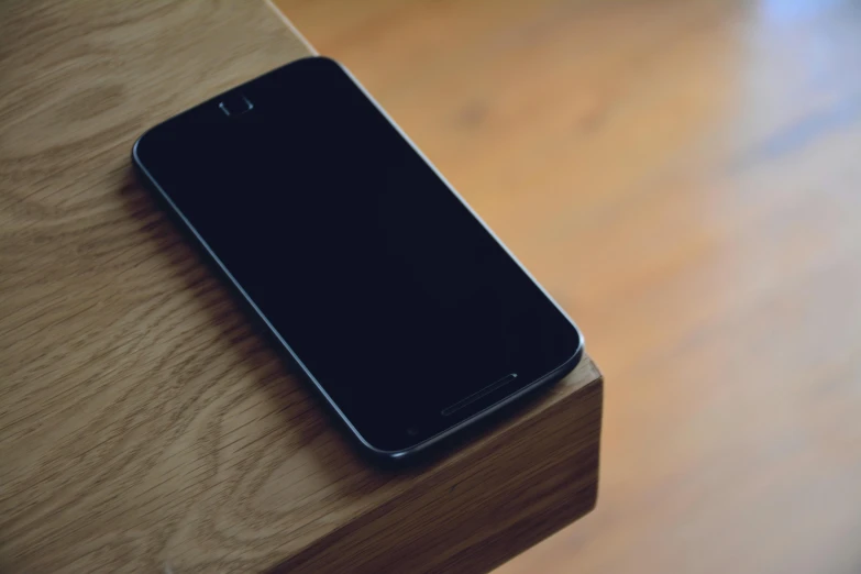 a cell phone sitting on top of a wooden table, by Niko Henrichon, unsplash, a portrait of an android, round corners, on a pedestal, material design