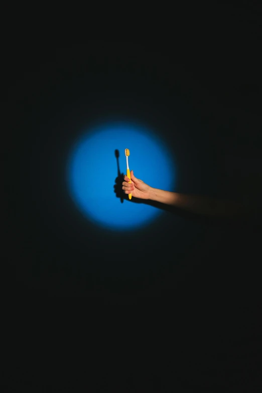 a hand holding a dark light on blue background