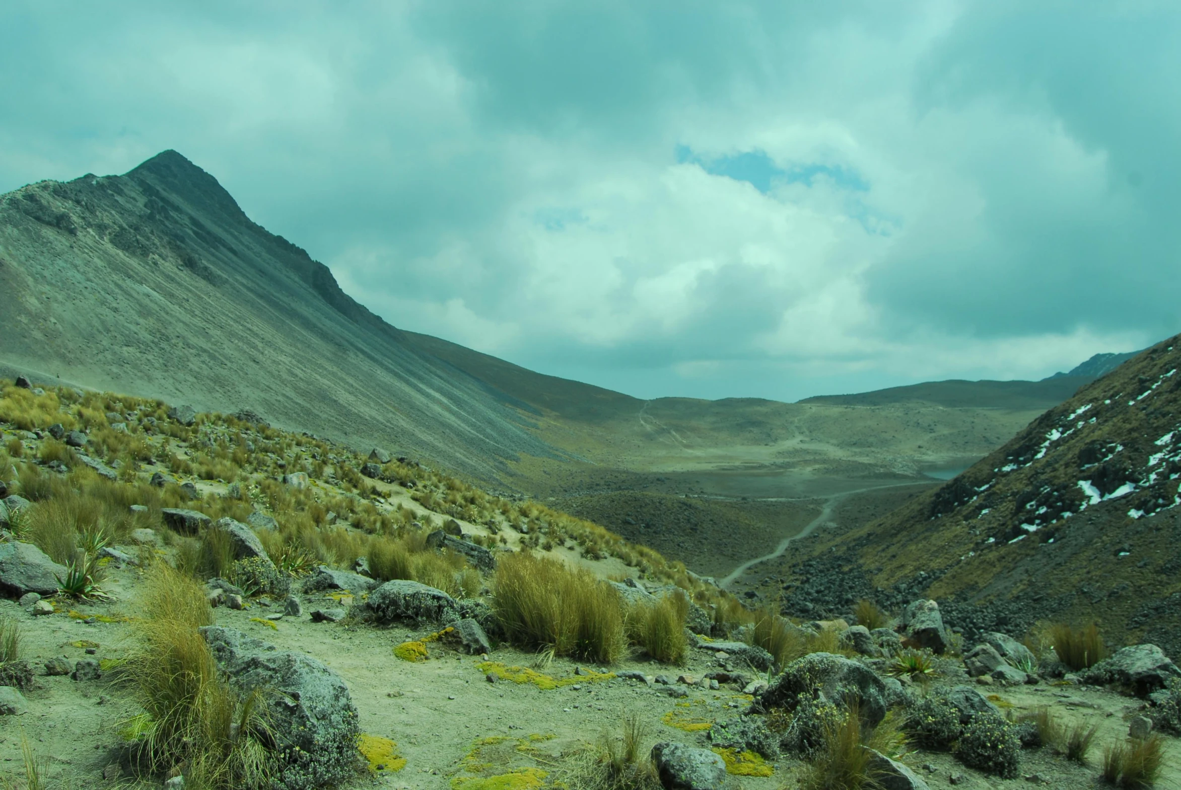 a dry, grassy plain surrounded by mountains and rolling clouds