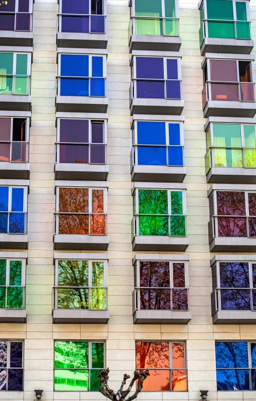 many colorful windows in a large building with a tree