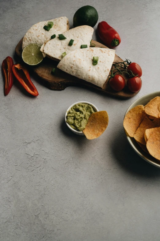 a plate of tortilla chips and a bowl of guacamole, a still life, pexels contest winner, on grey background, low - lighting, thumbnail, spicy