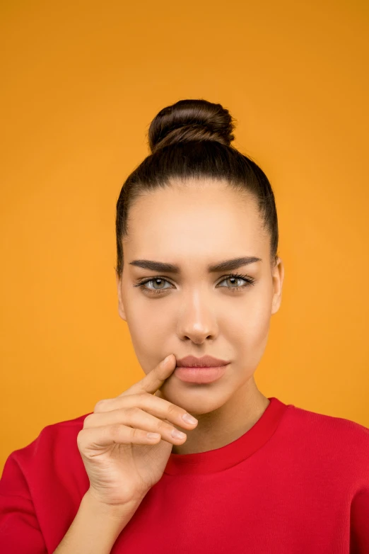 a woman in a red shirt holding her finger to her lips, trending on pexels, in front of an orange background, square nose, snot, h3h3