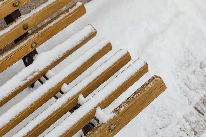 some wooden benches covered with snow during the day