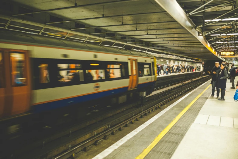 a group of people standing on a platform next to a train, by Carey Morris, unsplash, down in the sewers of london, avatar image, 2263539546], brown