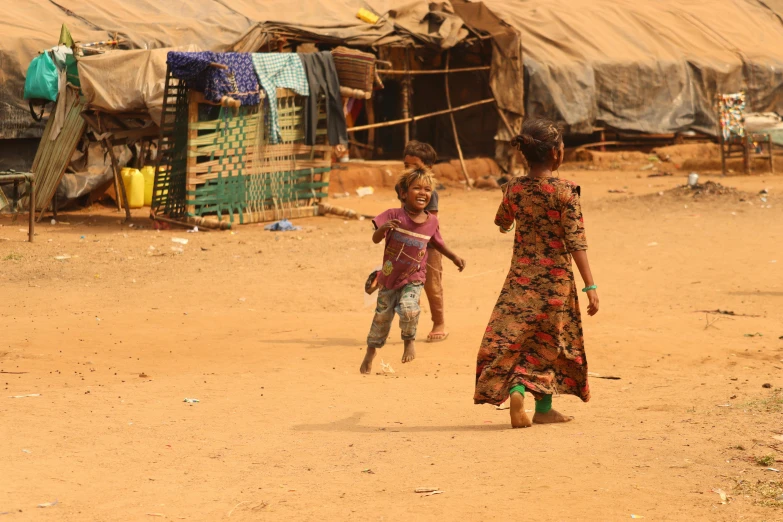 a couple of kids that are standing in the dirt, hurufiyya, a woman walking, on a village, running towards the camera