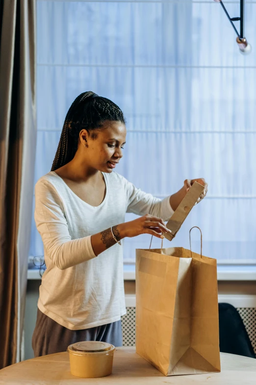 a woman in white shirt preparing brown bag on table