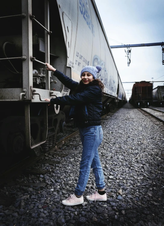 a woman standing next to a train on a track, profile image, isabela moner, journalism photo, 2 0 0 0's photo