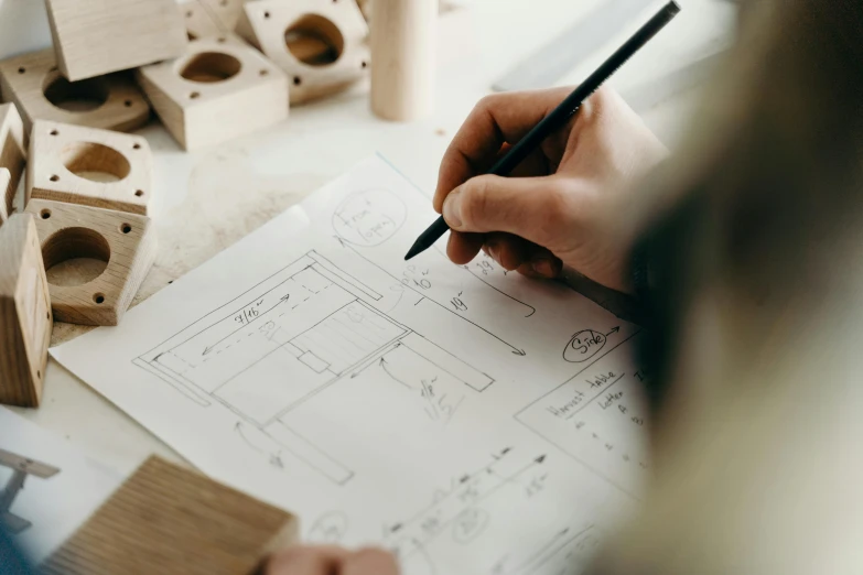 a person with a pencil is writing in front of some wooden blocks