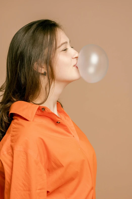 a woman in an orange shirt blowing a bubble, an album cover, trending on pexels, soft volume absorbation, profile image, jelly glow, brown